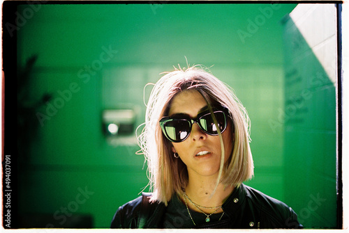 Blond woman on a green room with sunglasses and backlight photo