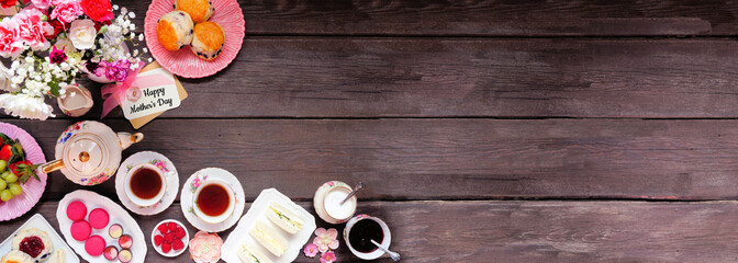 Mother's Day tea double border over a dark wood banner background. Greeting card, flowers, vintage tea set, finger sandwiches, chocolates, desserts and fruit. Copy space.
