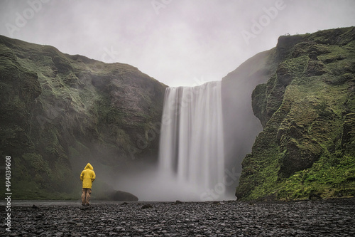 adventurer in front of famous Skogafoss waterfall in Iceland