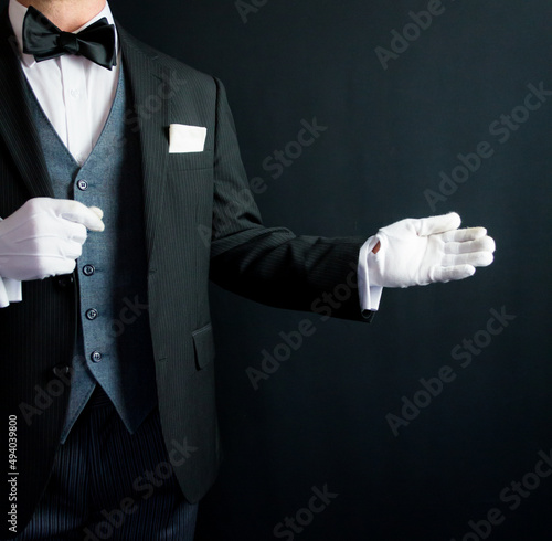 Portrait of Butler in Formal Suit and White Gloves With Welcoming Gesture. Concept of Service Industry and Professional Courtesy.
