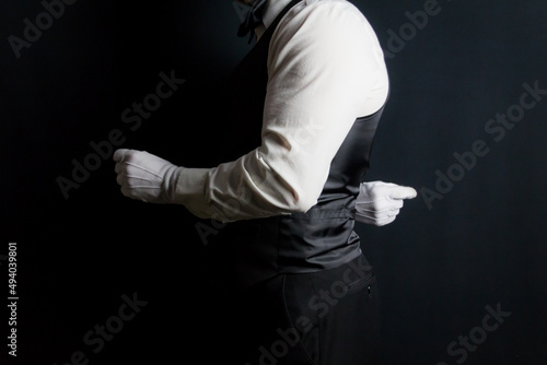 Profile Portrait of Butler or Waiter in Black Vest and White Gloves Standing at Elegant Attention. Concept of At Your Service.