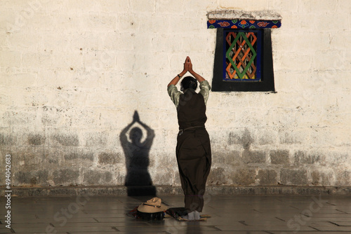 Person praying near a wall with a shadow in the Jokhang Temple in Lhasa, Tibet photo