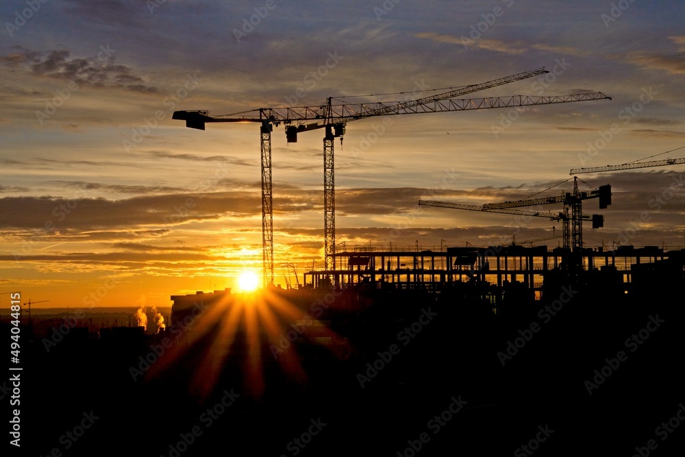 Construction cranes at sunrise at a building site in Tres Cantos, near Madrid Construction cranes at sunrise at a building site in Tres Cantos, near Madrid