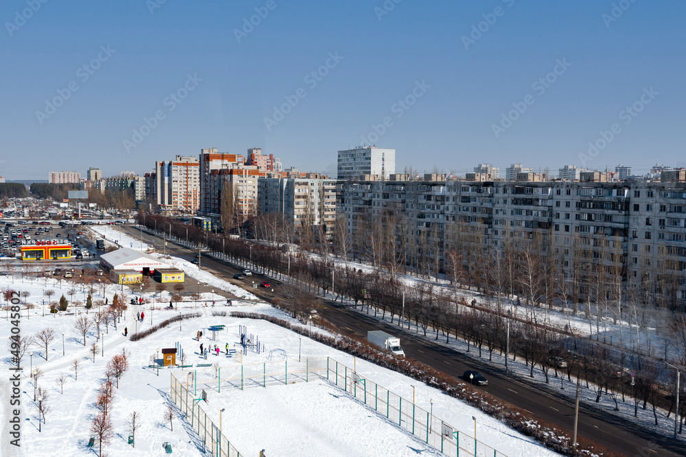 Fototapeta premium Photo of the avenue with residential buildings and city highways, from above. Urban landscape, in a winter setting, sunny bright weather.
