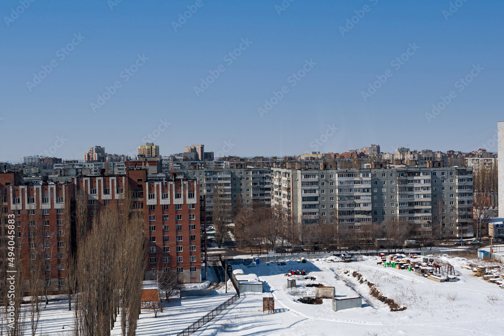 The development of a block of brown and white houses. Urban landscape, in a winter setting, sunny bright weather.