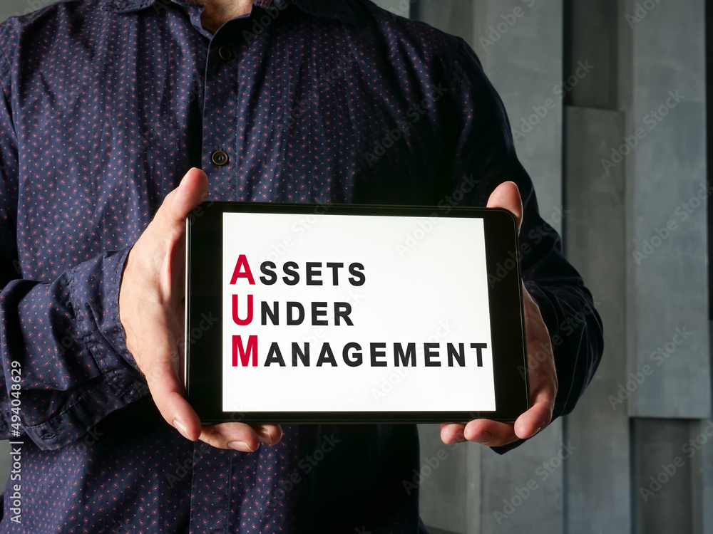 Assets Under Management AUM concept. Man shows tablet.