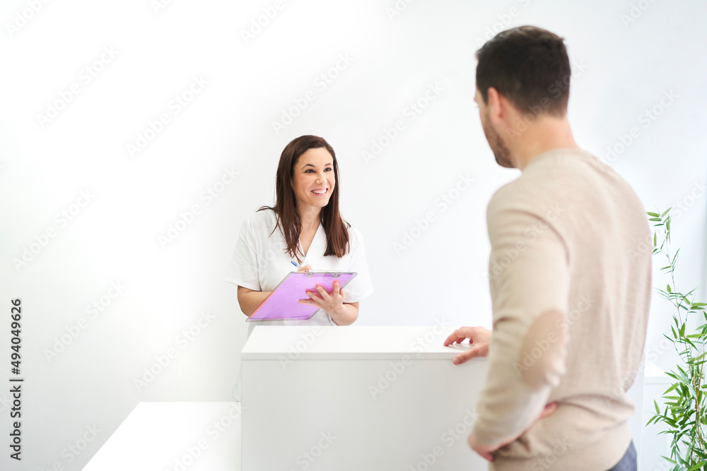 physiotherapist at the reception of the clinic fills out a client form physiotherapist at the reception of the clinic fills out a client form