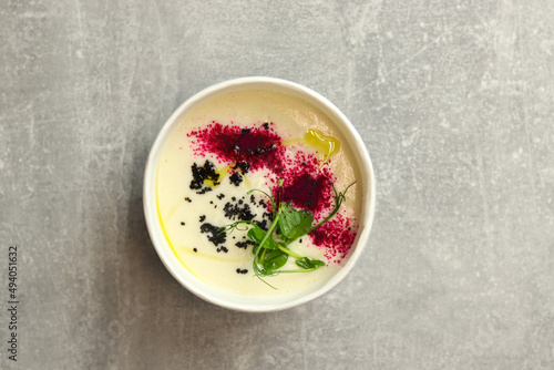 Cauliflower puree potato soup in round bowl on a gray background, top view. Vegetarian healthy food delivery concept