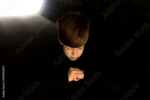 Boy praying in the dark, light at the end of the tunnel