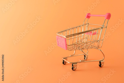 Empty metal small grocery cart. Yellow background. Sanctions concept, food crisis