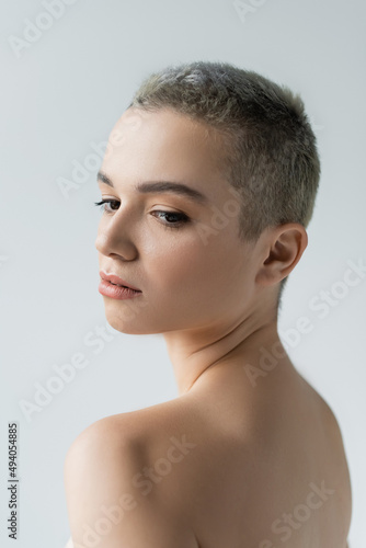 young woman with short hair and naked shoulders isolated on grey.
