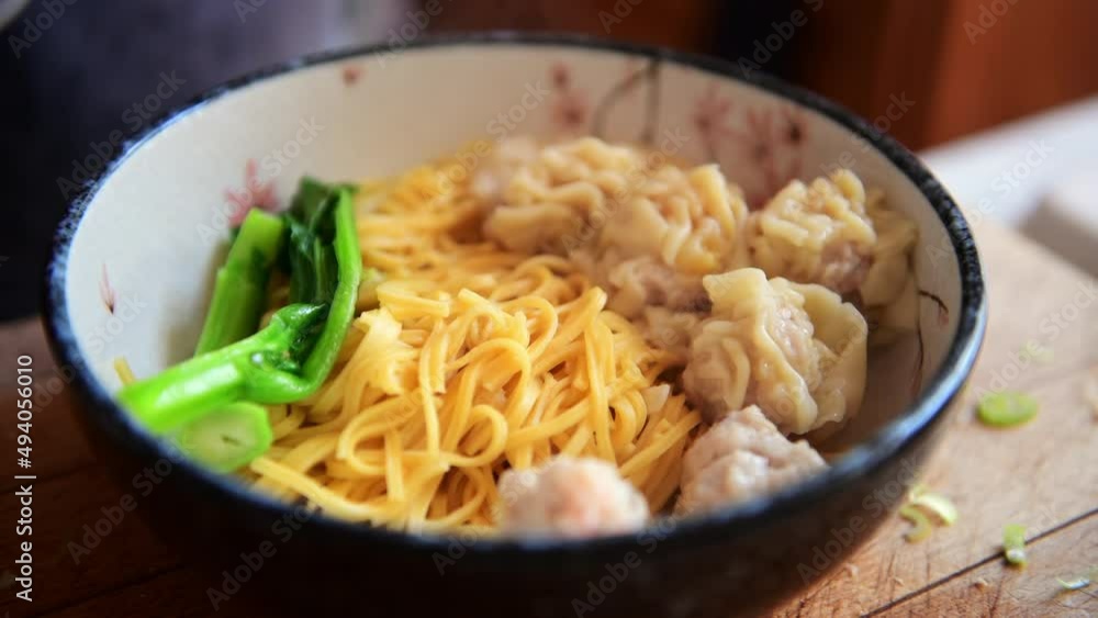 Putting green vegetables in a bowl of noodles. Putting green vegetables in a bowl of noodles.