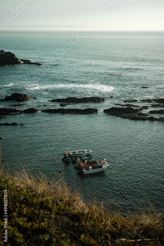 Boats sailing near to the rock formations in the sea in Costa Alentejana, Alentejo, Portuga photo