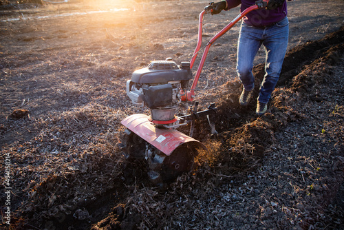 man cultivates the ground in the garden with a tiller  preparing the soil for sowing