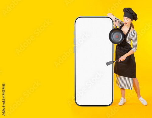 Chef mobile app. Woman chef demonstrates smartphone. Big phone in front of restaurant chef. Website recommendation for new restaurant. Space for advertising on phone display. Cook service ads