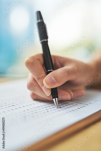 Exam in progress. Shot of a woman filling in an answer sheet for a test.