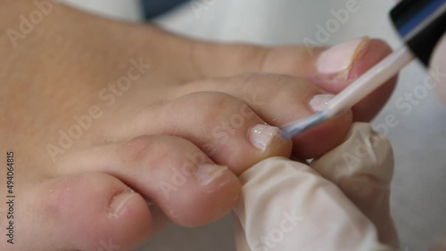 Piedi di una giovane donna che fa pedicure. Terapia del piede in una spa, Smalto sulle unghie, pulizia e taglio. photo