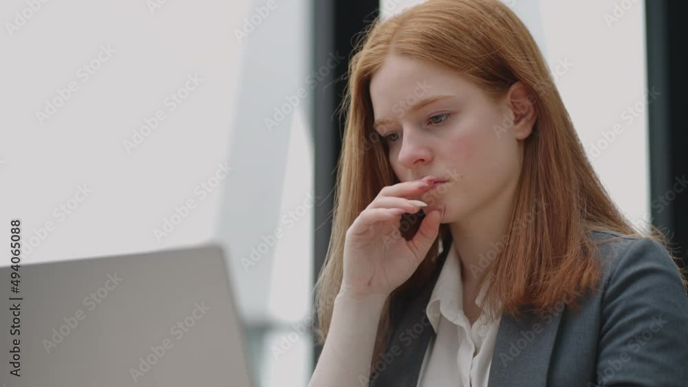 Thoughtful concerned redheaded woman working on laptop computer looking away thinking solving problem at office, serious woman search for inspiration make decision feel lack of ideas Thoughtful concerned redheaded woman working on laptop computer looking away thinking solving problem at office, serious woman search for inspiration make decision feel lack of ideas