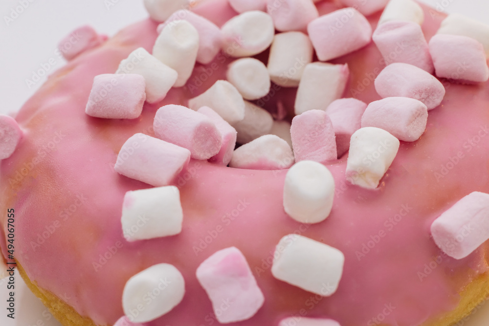 Close-up shot of pink tasty delicious sweet donut with colorful sprinkles on purple background. Dessert. Colorful frosted pink doughnut. Close-up shot of pink tasty delicious sweet donut with colorful sprinkles on purple background. Dessert. Colorful frosted pink doughnut.