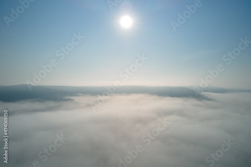 Fototapeta Naklejka Na Ścianę i Meble -  Aerial view from high altitude of earth covered with white puffy cumulus clouds on sunny day