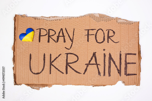 Close-up on hand holding banner with Pray for Ukraine text