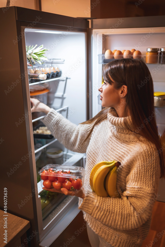 Woman arranging fresh groceries in freezer Woman arranging fresh groceries in freezer