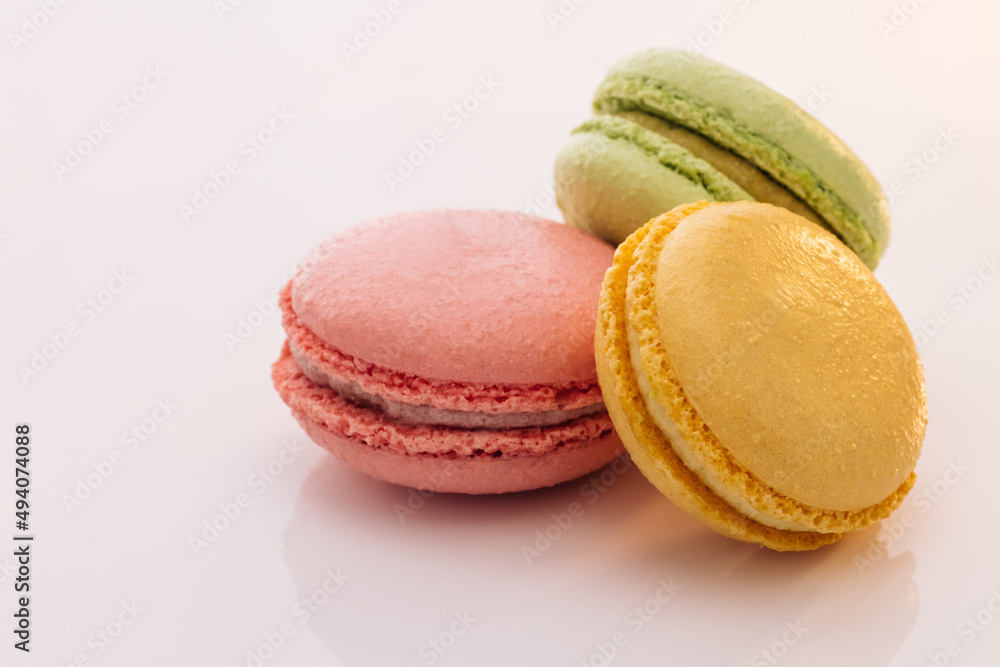 Three cookies macaroons are stacked on top of each other. Traditional French multicolored macaroon. Macaroons on white background. Food concept. Three cookies macaroons are stacked on top of each other. Traditional French multicolored macaroon. Macaroons on white background. Food concept.