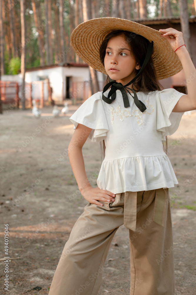 Stylish dark haired tween girl posing in backyard of country house in pine forest