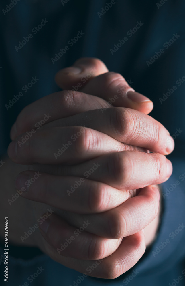 Man hands in praying position low key image Man hands in praying position low key image