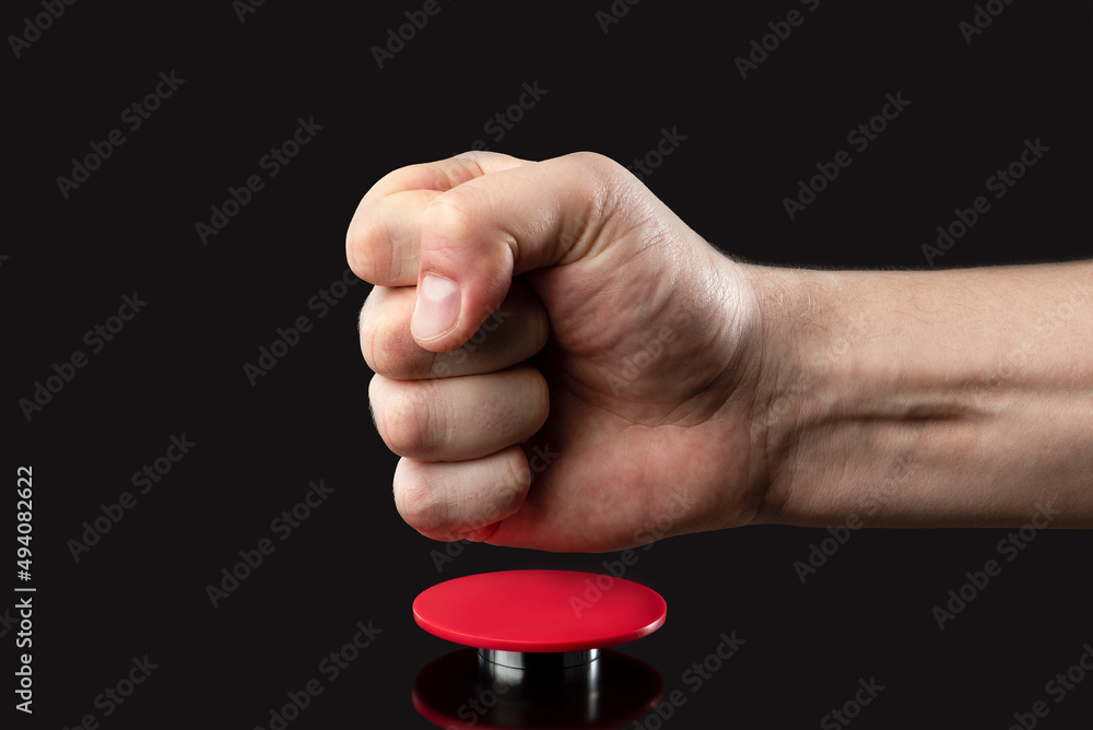 A man's hand presses a big red button. Red button on a dark background. The  threat
