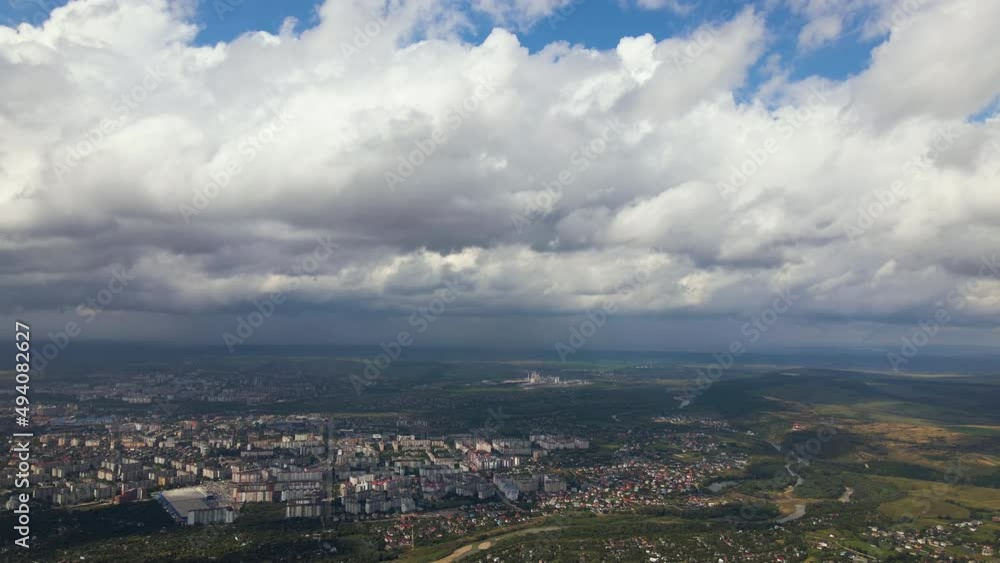 Aerial view from high altitude of distant city covered with puffy cumulus clouds forming before rainstorm Aerial view from high altitude of distant city covered with puffy cumulus clouds forming before rainstorm