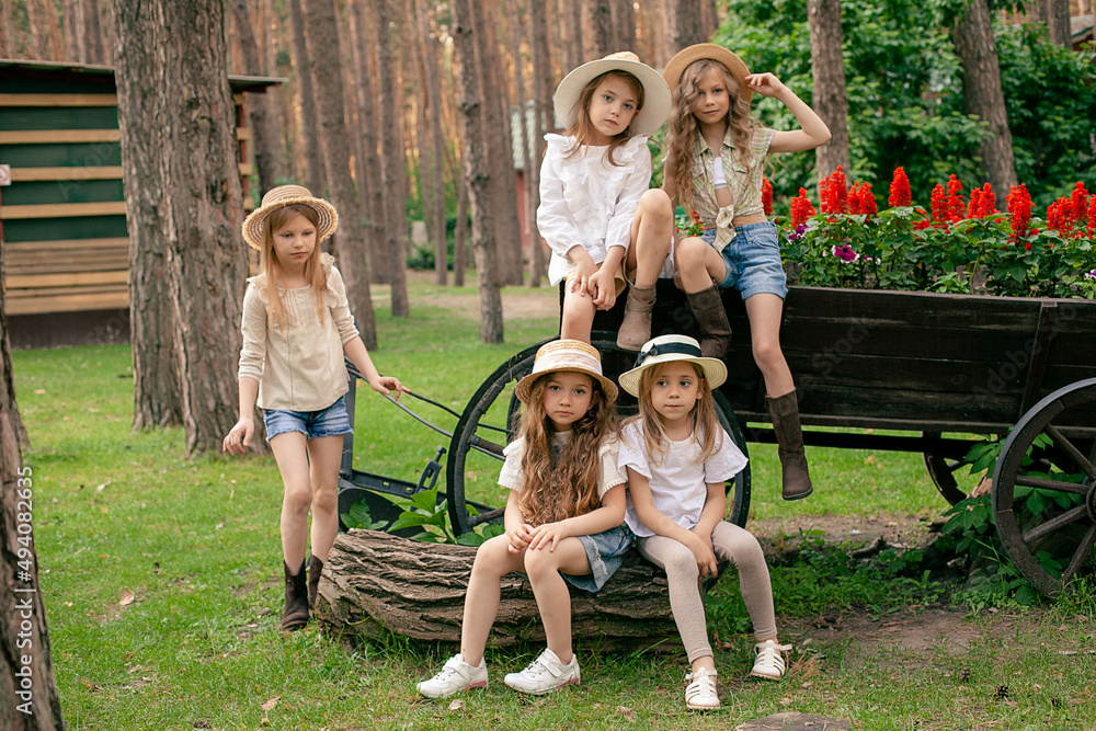Group portrait of preteen girls near old wooden cart used as flower bed in park Group portrait of preteen girls near old wooden cart used as flower bed in park