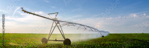 Agricultural irrigation system watering corn field in summer photo