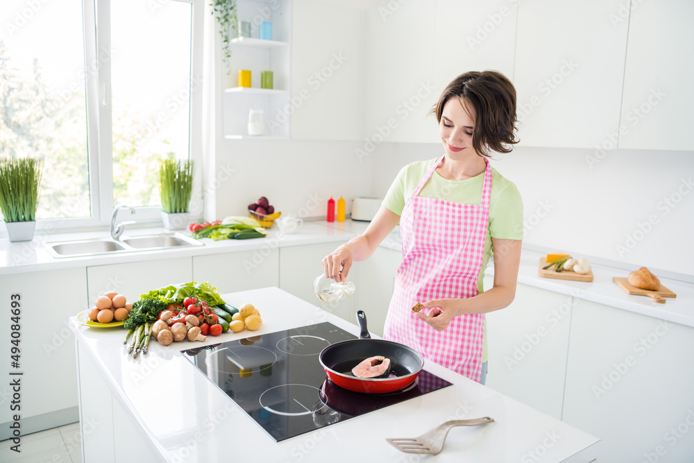 Photo of pretty positive lady frying fresh fish pouring oil enjoy free time kitchen indoors Photo of pretty positive lady frying fresh fish pouring oil enjoy free time kitchen indoors