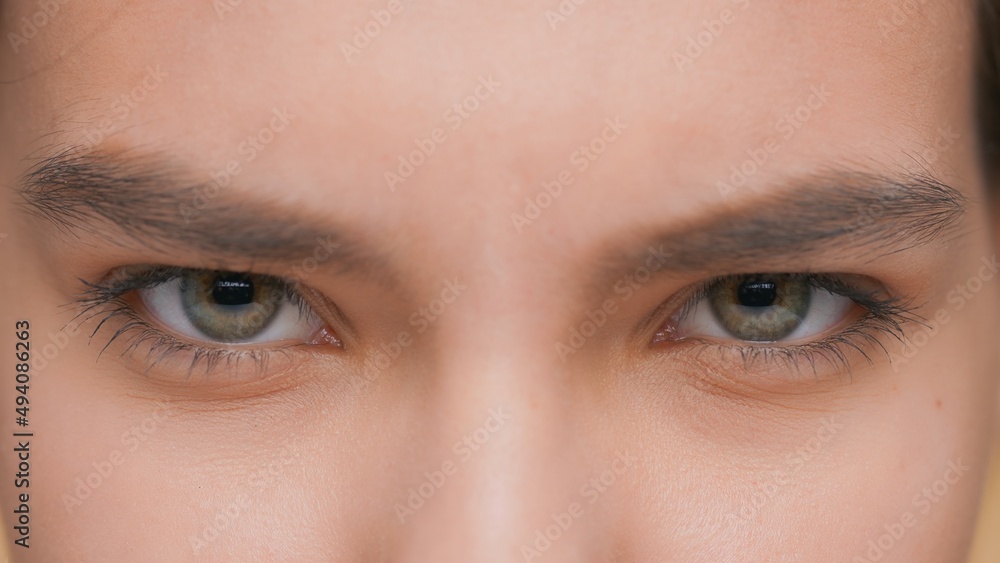 Extreme close-up of young woman opens her eyes and looks at camera, blinks and smiles Extreme close-up of young woman opens her eyes and looks at camera, blinks and smiles