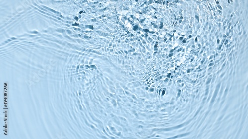 Water splashing and making ripples on blue background | skincare background, cleanser commercial concept