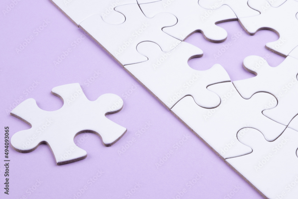Puzzle pieces on lilac surface. White jigsaw game grid texture. Matching, inserting last missing part. Business and teamwork problem solving background. Copy space for add text, close up. Puzzle pieces on lilac surface. White jigsaw game grid texture. Matching, inserting last missing part. Business and teamwork problem solving background. Copy space for add text, close up.