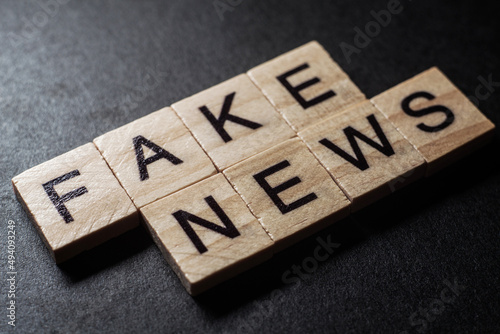 Macro of the words fake news formed by wooden blocks on black background photo