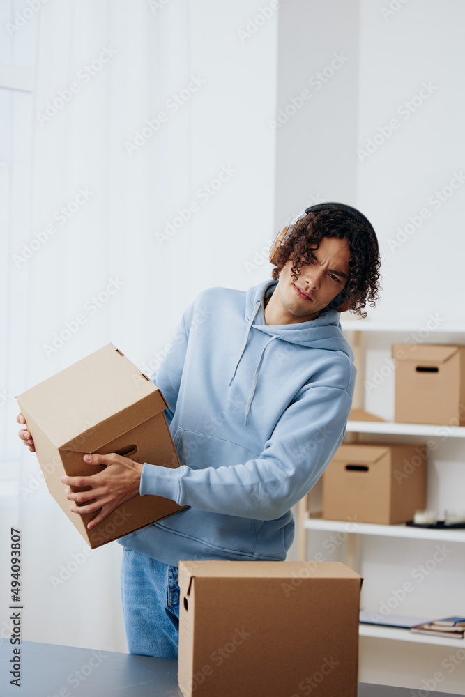 guy with curly hair cardboard boxes in the room unpacking in headphones Lifestyle guy with curly hair cardboard boxes in the room unpacking in headphones Lifestyle