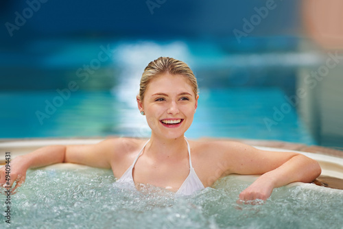 The bubbles feel amazing. Shot of a young woman relaxing in the jacuzzi at a spa. © Thurstan H/peopleimages.com
