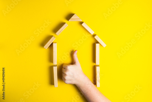 Top view of child's hand close up building blocks showing ok, house, wooden hut