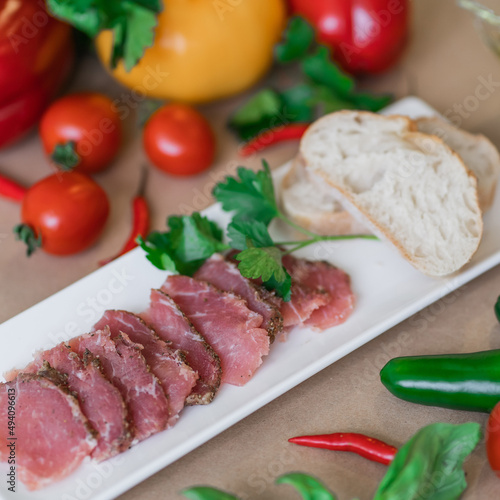 salted meat on a plate with basil and tomatoes