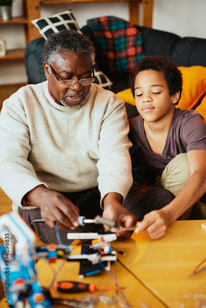 Fototapeta premium A granddad and his grandchild building a robot at home.