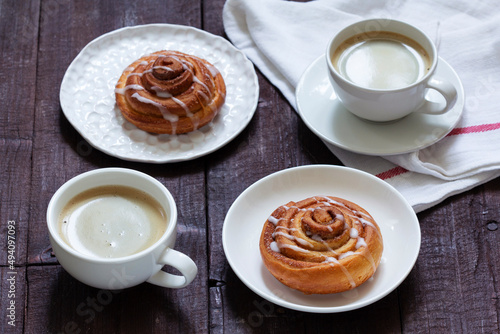 Cinnamon buns with icing served with coffee. Rustic style.