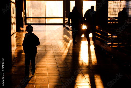 Silhouette of a boy and people walking through the hallway 