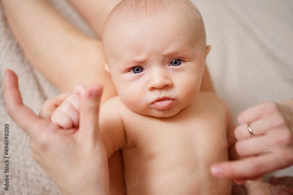 sad cute naked baby lies on his mother's feet. maternal and child health. sad cute naked baby lies on his mother's feet. maternal and child health.