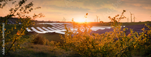 Solar panels station and wind power generator equipment at sunset time