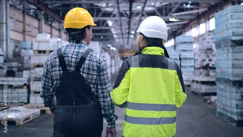 Follow footage of employees male and famale warehouse worker engineer in hard hat working. walking through logistics center warehouse factory construction site logistics architect businessman man photo