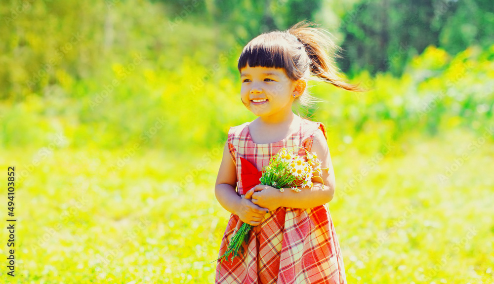 Portrait of happy smiling little girl child outdoors walking in sunny summer park