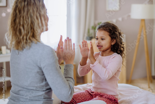 Happy mother with her little daughte playing clapping hands game on bed at home. photo